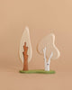 Two trees from the Enchanted Woodland Farm Set, one with a brown trunk and one with a white trunk, stand on a green base against a beige background. Ideal for imaginative play and pairing with handmade wooden or Ostheimer animals.