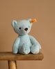 The 10-inch My First Steiff Blue Teddy Bear, featuring "My First Steiff" embroidered on its foot and the signature ear tag, sits on a wooden stool against a beige background—the perfect soft teddy bear gift for babies.