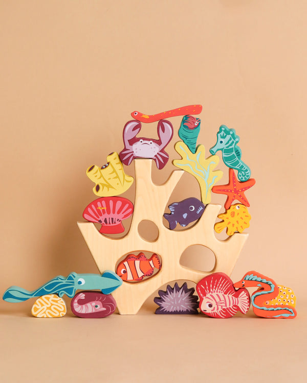 Colorful wooden stacking coral reef puzzles arranged on a beige background, featuring a crab, seahorse, corals, and various fish, creating an educational undersea scene with sea creatures.