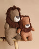 Two plush lions from the Safari Friends Collection rest on a wooden surface against a beige background. With brown manes and soft sewn faces, one is slightly larger. Features exquisite handmade details. Product: PRE-ORDER Maileg Safari Friends - Big Lion (ships in February).