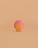 The Bumbu Handmade Wooden Pink Seashell, a small Montessori-inspired toy with an orange-to-pink gradient, is centered on a plain beige background.