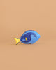 The Bumbu Handmade Wooden Royal Blue Fish, featuring blue and yellow painted details, is a sustainable Montessori toy displayed on a plain light brown background—perfect for mindful play.