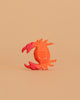 The Bumbu Handmade Wooden Red Crab features bright orange-red hues, white dots, and stylized curved claws. Crafted from sustainable wood, it stands upright on a beige background—ideal for Montessori-inspired play or decorative display.