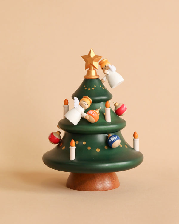 A decorative wooden Angels Decorating Christmas Tree music box adorned with small candles and ornaments including angels and baubles, set against a neutral beige background.