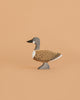 The Bumbu Handmade Wooden Wild Goose is a small, handcrafted wooden toy painted in brown, gray, black, and white and stands on a plain light tan background.