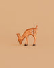 The Bumbu Handmade Wooden Fawn Eating is a small, brown wooden toy with white spots, depicted grazing with its head lowered—an eco-friendly choice ideal for imaginative play.