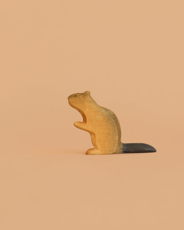 The Bumbu Handmade Wooden Beaver is a small, handcrafted toy with a dark tail, standing upright on a light peach background—perfect for Montessori-inspired play.