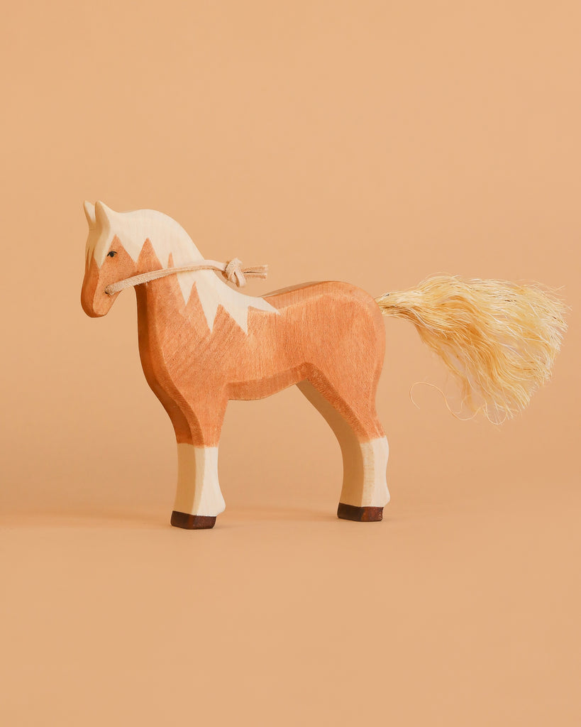 The Maileg Big Brother Horseback Adventure Set features a handmade wooden horse with a light brown body, cream mane and legs, and a rope tail, displayed on a matching beige background.