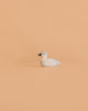 The Bumbu Handmade Wooden Baby Swan, a small white handcrafted wooden toy with a black beak, sits on a plain, light peach background.