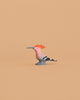 The Bumbu Handmade Wooden Hoopoe Bird is a small, handcrafted wooden figurine featuring an orange crest, pink body, gray beak, and black-and-white striped tail set against a plain beige background.