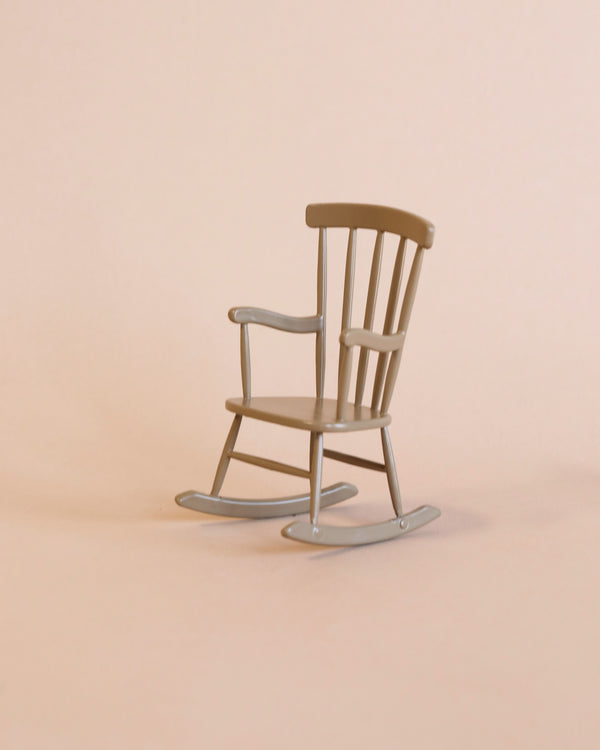 A Maileg Rocking Chair, Mouse - Light brown is centered against a matching light beige background. The rocking chair, perfect for a relaxing chair, has classic design elements, including a slatted back and gently curved rockers.