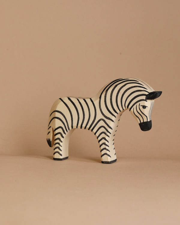 A small, handcrafted Ostheimer Zebra figurine on a beige background. The toy showcases a simple, stylized design with black and white stripes, a black mane, and small, rounded features, giving it a playful and minimalist appearance perfect for imaginative play.