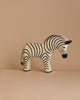 A small, handcrafted Ostheimer Zebra figurine on a beige background. The toy showcases a simple, stylized design with black and white stripes, a black mane, and small, rounded features, giving it a playful and minimalist appearance perfect for imaginative play.