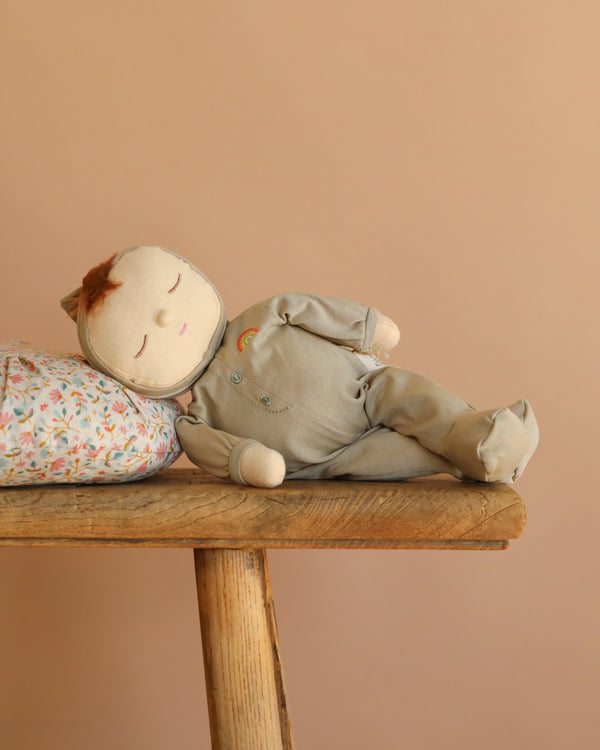 The Olli Ella Dozy Dinkum - Pickle is a soft fabric baby doll with closed eyes, light brown hair, and a light green outfit—ideal as a first toy or for Dozy Dinkum fans.