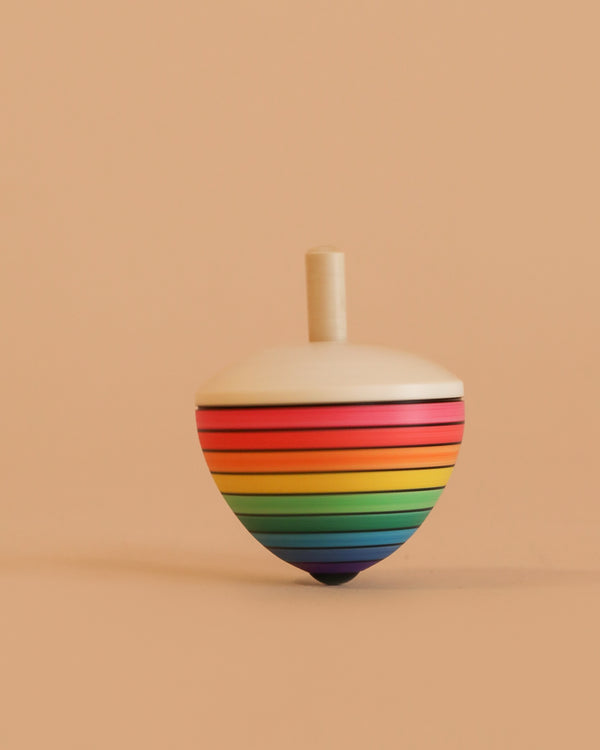 The Mader Rainbow Egg Spinning Top - Red is crafted from maple wood, featuring colorful rainbow stripes and a handle, shown standing upright against a plain beige background.