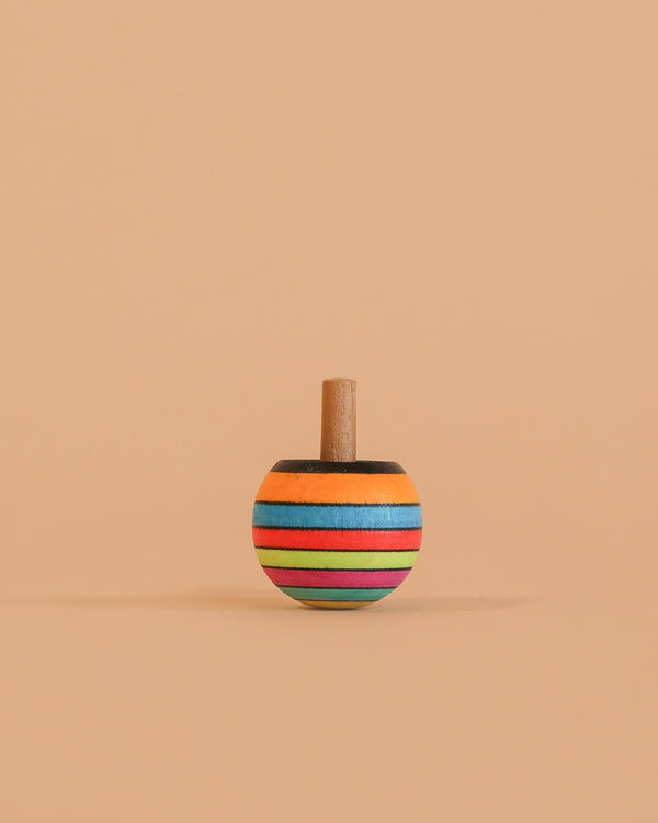 The Mader Turn-Over Top - Striped, made of maple wood with orange, blue, green, red, and black horizontal stripes, stands upright on a beige background.