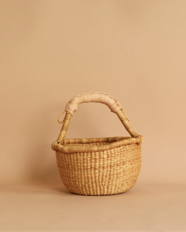 A woven basket with a beige leather handle.