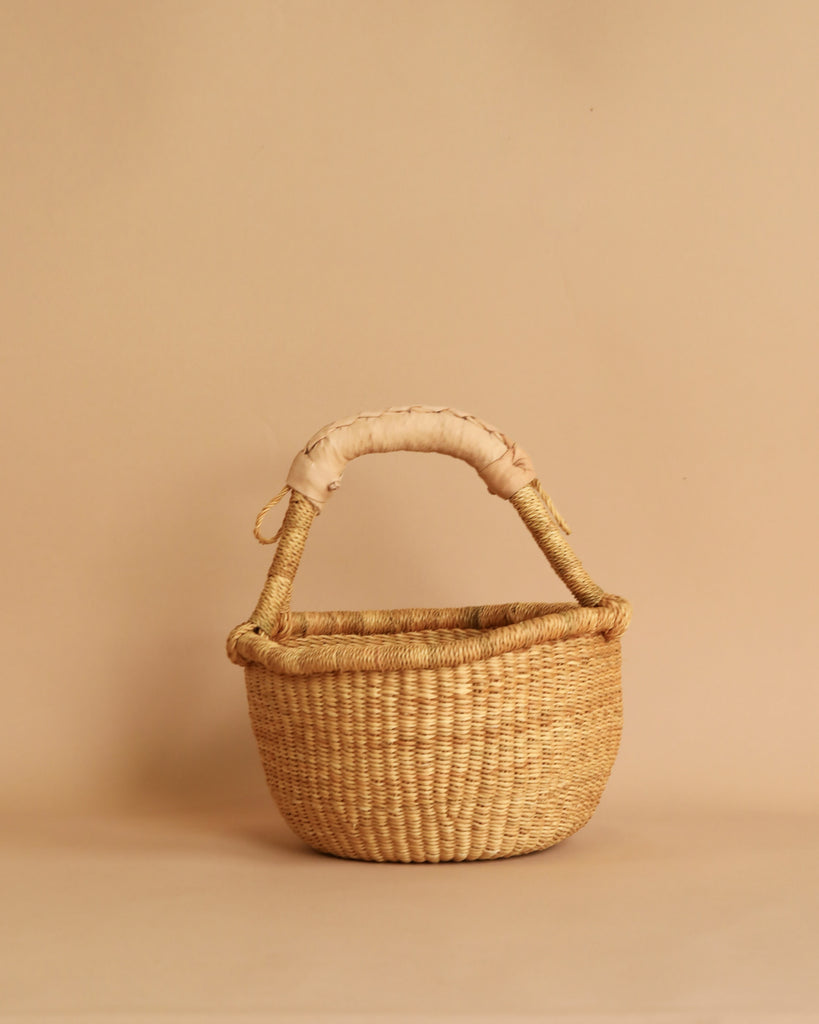 A woven basket with a beige leather handle.