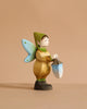The Bumbu Handmade Wooden Winged Elf with Lamp Set features a small, handcrafted wooden elf fairy with blue wings, a green hat, tan clothes, and a blue-and-white lantern set against a plain beige background.