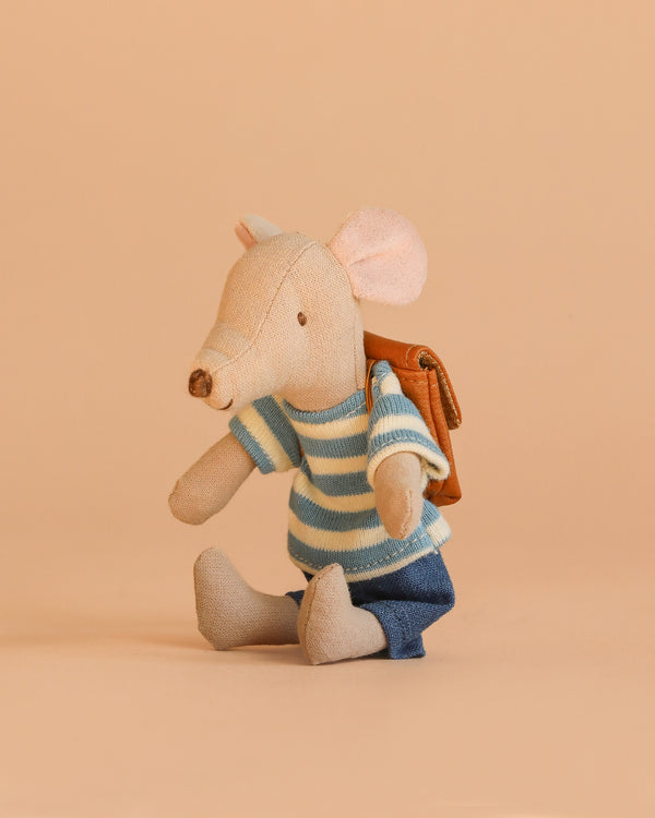 The Maileg Tricycle Mouse, Big Brother - Brown wears a blue and white striped shirt, blue pants, and a brown backpack as it sits on a beige surface against a matching background.