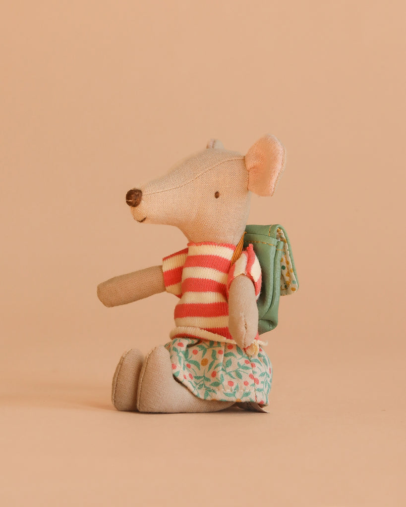 The Maileg Tricycle Mouse, Big Sister - Green wears a red and white striped shirt, green patterned skirt, and green backpack, sitting upright against a plain beige background.
