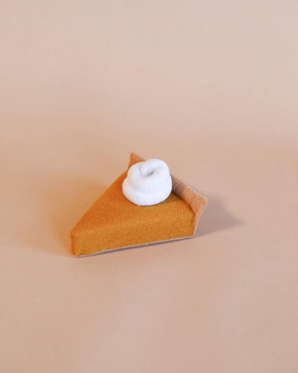 A 4.5x3.5" Handmade Felt Pumpkin slice with a dollop of white felt whipped cream on top, positioned on a plain beige background.