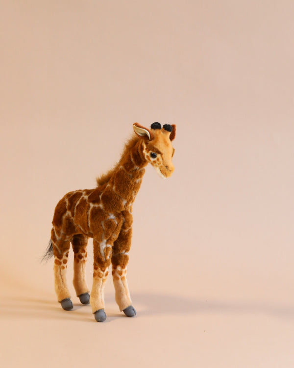 A Giraffe Stuffed Animal standing on a plain light beige background, featuring realistic detailing and soft fur with distinct giraffe patterning and gentle eyes, crafted from high quality man-made materials.