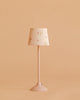 The Maileg Floor Lamp, Miniature - Powder features a pastel pink base and floral-patterned shade, displayed on a matching pink surface with a solid peach background.
