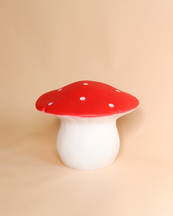 A ceramic stool shaped like a **Medium Red Mushroom Lamp**, with a glossy red cap dotted with white spots and a smooth white stem, perfect as children's room decor, set against a plain beige background.
