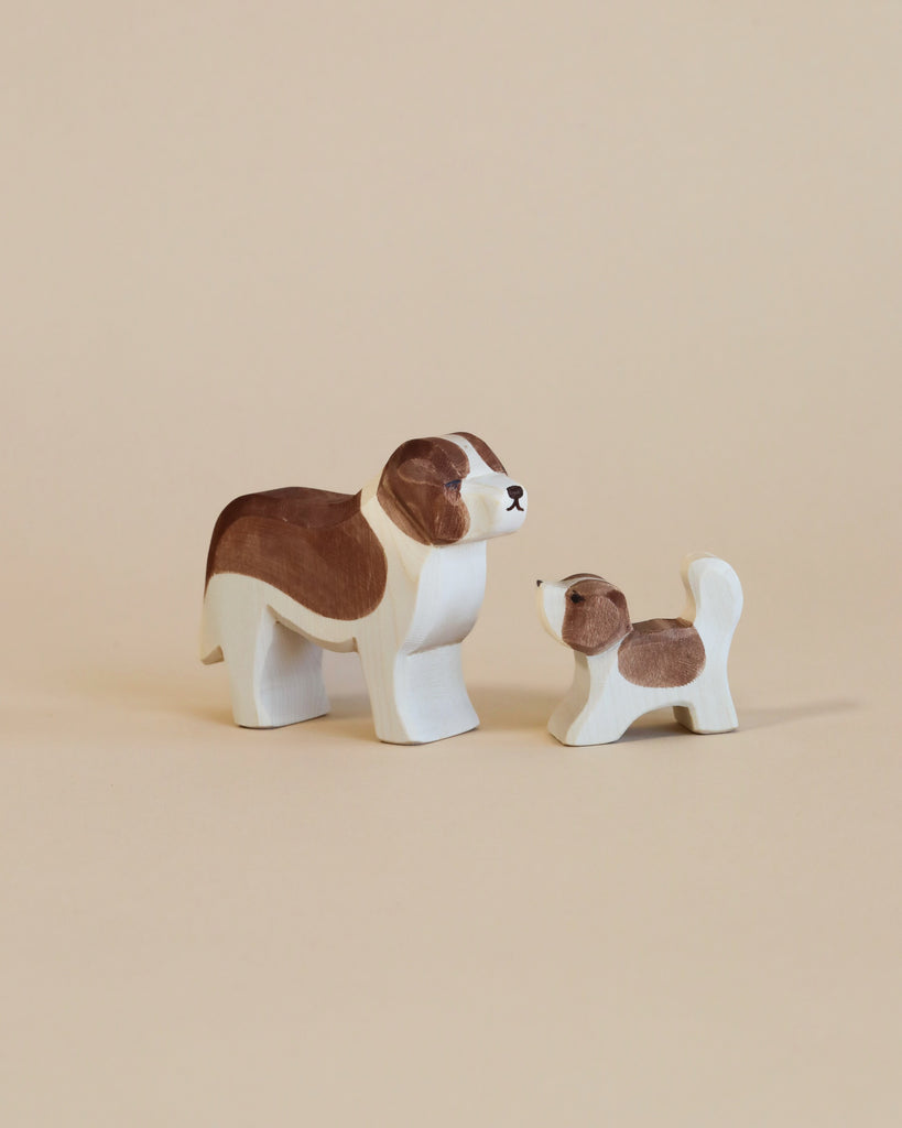 Two Ostheimer Saint Bernhard Dog figurines, one large and one small, painted in white and brown, facing each other on a light beige background.