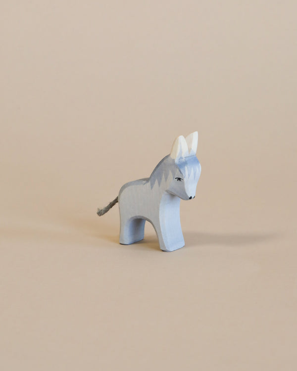 A handcrafted Ostheimer Donkey - Small with a blue and white paint finish stands against a beige background. The donkey has distinct dark eyes and a small tail detail.