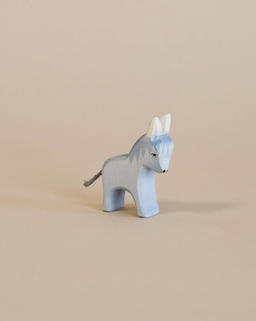 A handcrafted Ostheimer Donkey - Small with a blue and white paint finish stands against a beige background. The donkey has distinct dark eyes and a small tail detail.