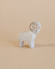 A small Ostheimer Ram figurine with a prominent spiral horn and detailed carving, standing against a plain beige background.