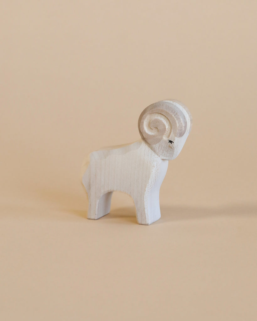 A small Ostheimer Ram figurine with a prominent spiral horn and detailed carving, standing against a plain beige background.