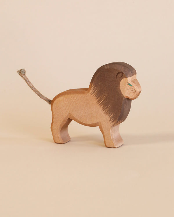 A handcrafted Ostheimer Lion - Male figurine stands against a light beige background, featuring a smooth finish and visible wood grain, with detailed carving for the mane and tail.