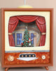 A vintage-style TV labeled "Christmas Music TV With Nutcracker" lights up with a decorative scene featuring a Christmas tree and two figures, a man and woman, on stage framed by red curtains. This scene captures the essence of festive holiday performance, accompanied by enchanting Christmas melodies.