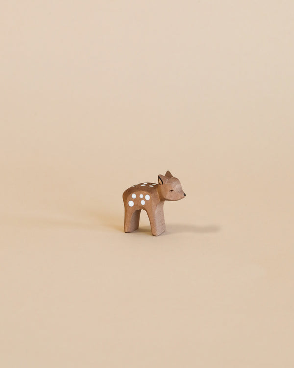 A small handcrafted Ostheimer Small Deer - Head Low figurine with white spots on a plain beige background. The deer is standing, with its head turned slightly to the left.