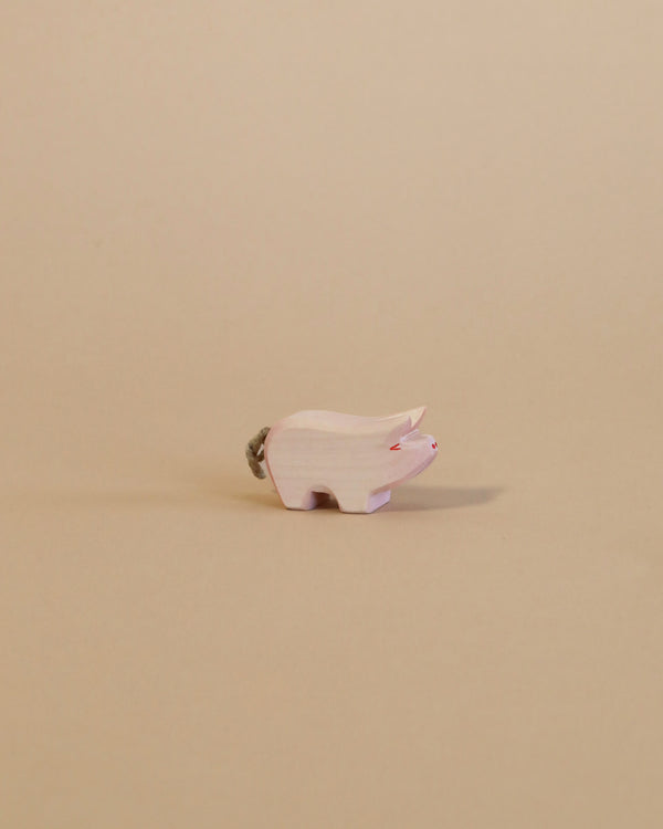 A small Ostheimer Piglet, handcrafted from sustainably sourced materials, positioned sideways on a plain beige background. The piglet has visible grain textures and painted details like eyes and nostrils.