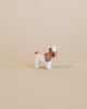 A small donkey from the Ostheimer Handmade Wooden Farm Animals Set, painted white and brown with non-toxic paints, stands on a plain beige background.