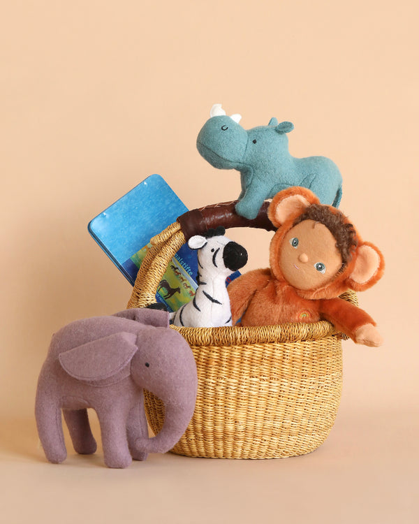 An Easter Basket Set filled with felt safari animals including a hippo, elephant, monkey, and a dog, with a children's book peeking out, against a soft beige background.