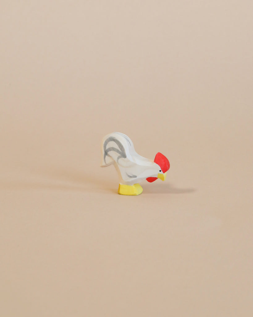 A small handcrafted Ostheimer Rooster - White with a red head and yellow feet positioned on a plain beige background.