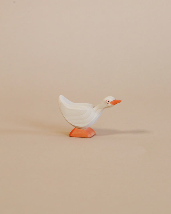 A small, white Ostheimer Goose - Standing figurine with orange feet stands against a plain beige background. The goose has a simple, streamlined design with visible brush strokes.