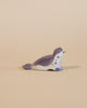 A handcrafted Ostheimer Sea Lion - Head Low toy seal painted in shades of gray and white, positioned on a plain beige background. The seal is depicted in a lying pose with its head turned slightly to the side.