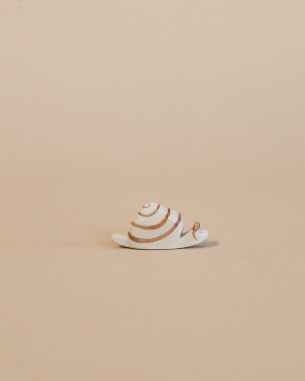 A small handcrafted Ostheimer Snail figurine with spiraled shell patterns, positioned on a plain beige background.
