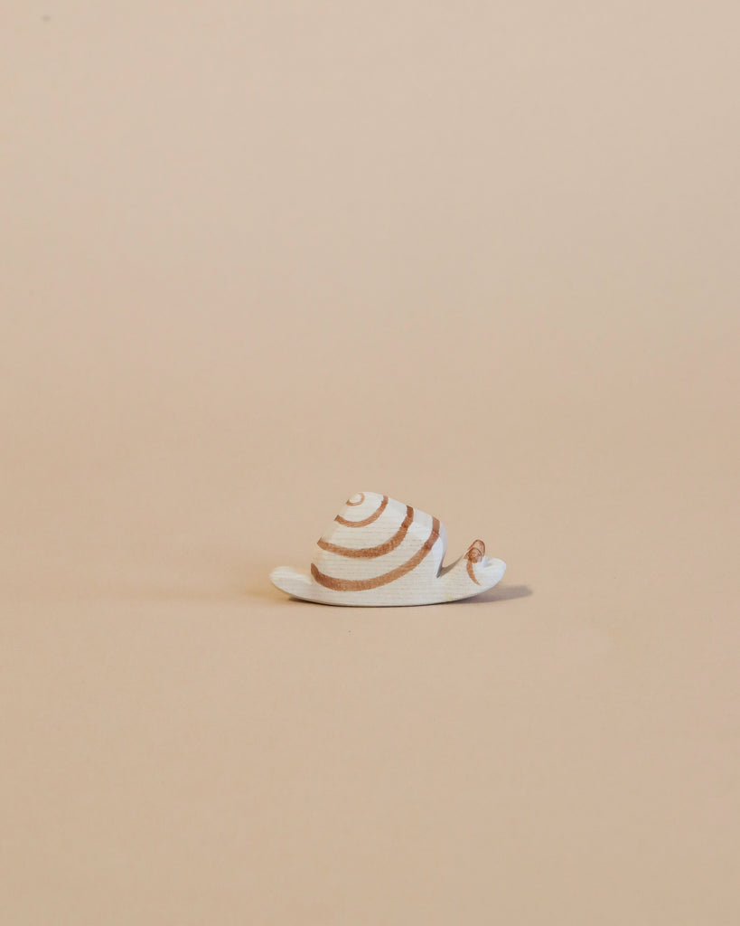 A small handcrafted Ostheimer Snail figurine with spiraled shell patterns, positioned on a plain beige background.