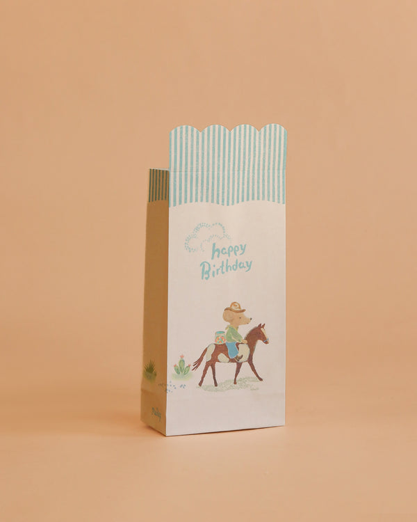 The Maileg Goodie Bags - Happy Birthday - Cowboy (12 Pieces) feature pastel colors, blue stripes, a cowboy on horseback illustration, and "happy Birthday" text—perfect for small gift or party favor bags.
