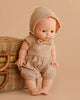 The Minikane Vintage Baby Boy Doll (13") - Louis with Clothing stands beside a wicker basket, both set against a beige background.