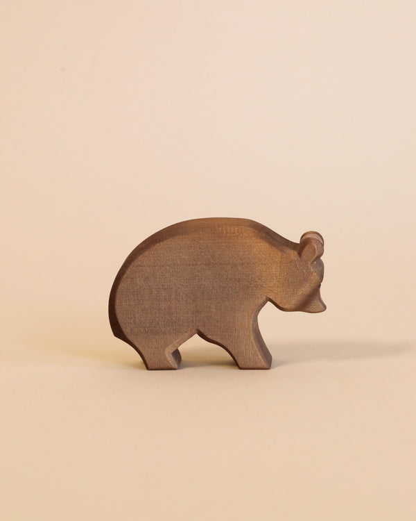 A handcrafted Ostheimer Bear figurine stands against a light beige background, showcasing its silhouette with smooth edges and a visible grain texture.