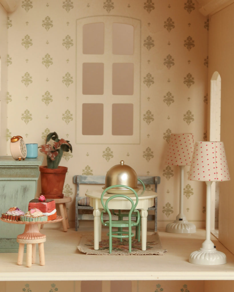 Create a charming Maileg mice scene with the Maileg Fully Furnished Dollhouse Set + Gift With Purchase, including a vintage-style dining room with round table, green chair, cake stand, two polka-dot lamps, plant, and patterned wallpaper.