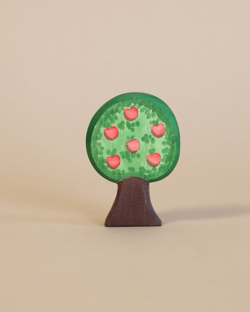 A small handcrafted Ostheimer Apple Tree stand-up figure painted with a green canopy adorned with red heart-shaped leaves, set against a plain beige background.